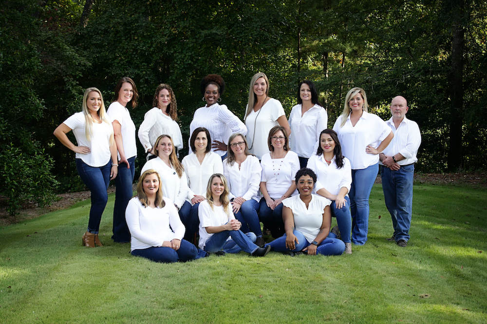 Employees dressed in white shirt and jeans in a natural setting, smiling